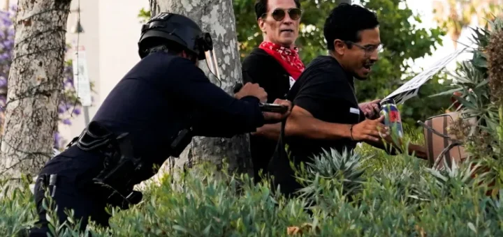A member of law enforcement disperses people as protests against federal immigration sweeps continue, in downtown Los Angeles, California